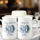 80ste verjaardag Proost 80 jaar Bloemen Nummer Porselein Kop<br><div class="desc">mok 80e verjaardagsverjaardag, met volledig bewerkbare bewoordingen om te personaliseren zoals u wilt, zoals "Happy Birthday [name]" en / of "Proost aan 80 jaar". Het ontwerp heeft nummer 80 versierd met rozen knoppen, bloesems en gebladerte in de tinten kustblauw en zand. Subtiel vrouwelijk en elegant design met waterverf bloemstukken, verfspatten...</div>