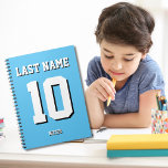 Aangepast lichtblauw Achternaam Sports Jersey Numb Notitieboek<br><div class="desc">De naam,  het aantal en de dalingsschaduw zijn klantgericht zodat kunt u een sportief uitziend maar nuttig notitieboek uniek maken en aan uw favoriete sportteamkleuren of kamerdecor aanpassen. Lichtblauwe achtergrond.</div>