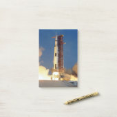 Aarde schudt als Saturn V de hemel doorklieft naar Post-it® Notes (Op bureau)