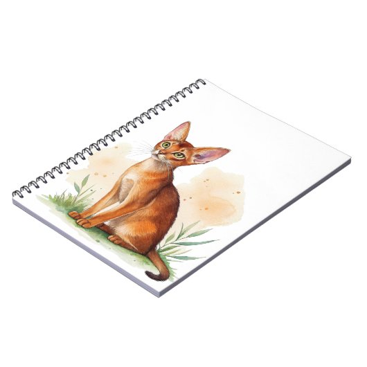 Abessijnse kat omringd door zachte kleuren en groe notitieboek (Linkerzijde)