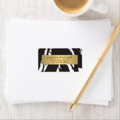 Abstracte zwarte penseelstreken met gouden naamlab etiket (Insitu)