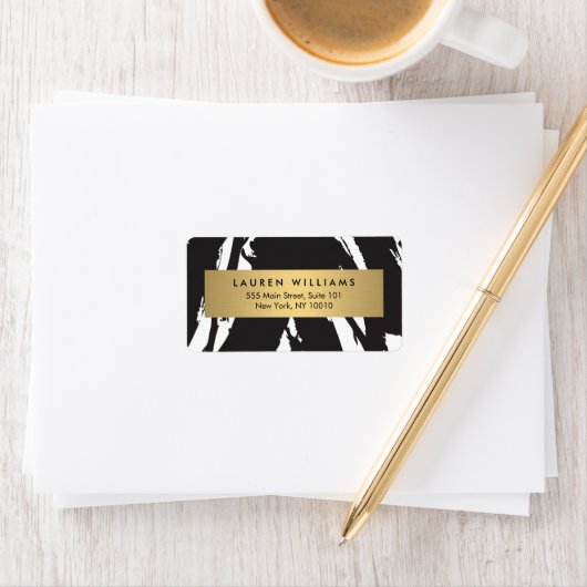 Abstracte zwarte penseelstreken met gouden naamlab etiket (Insitu)