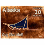 Alaska Dog Sled Mail Postage Stamp Fotobeeldje Magneet<br><div class="desc">Het poststempel van 20 Nugget is voorzien van een denkbeeldige onafhankelijke Alaska die de hervatting van de hondenstrook herdenkt. Een moderne hondenslede wordt voorgesteld in plaats van een afbeelding met een karibou (rendierbont). De slede heeft een blauwe tas met daarin de vlag en tekst van Alaska met de tekst "ALASKA...</div>