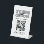 Bachelor QR Code Party Koop Drink Shot Team Groom Reclamebord Met Voetstuk<br><div class="desc">Koop de bruidegom om een drink te zijn! Aangepaste vrijgezellenfeest QR Codetafel sokkel ontwerp voor uw vrijgezellenfeest kenmerken "TEAM GROOM" in vet licht grijs type. Pas de naam van de bruidegom aan in zwart schrift op een heldere witte achtergrond. De titel van het evenement of vrijgezellenfeest wordt hieronder in het...</div>