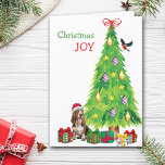 Basset Hound Hond, Vogel en Kerstboom Feestdagen Kaart<br><div class="desc">Op de voorkant van deze kerstkaart draagt een vrolijke Basset Hound dog een rood-wit Sinterklaasfeest pet terwijl hij naast een kerstboom zit. Licht verpakte cadeaupakketten zijn verspreid over, en een goudvink landt op de kerstboom. De rode en groene tekst zegt "Christmas JOY". Binnen is gestileerde tekst die VROLIJK KERSTMIS zegt,...</div>