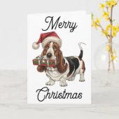 Basset Hound met Kerstman hoed cadeau in de bek Kaart (Gele Bloem)