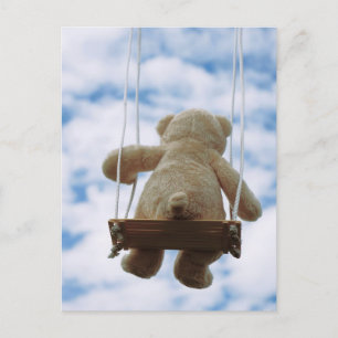 Beertje op schommel met bewolkte blauwe lucht. briefkaart
