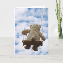 Beertje op schommel met bewolkte blauwe lucht. feestdagen kaart