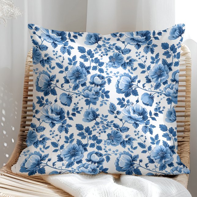 Blauw en wit cottage bloemmotief kussen (Navy Blue and White Cottage Floral Pattern Throw Pillow in a sunny rattan armchair.)
