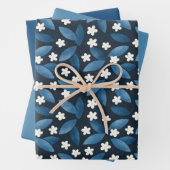 Blauwe bladeren en witte bloemen op donkere achter inpakpapier vel (In situ)