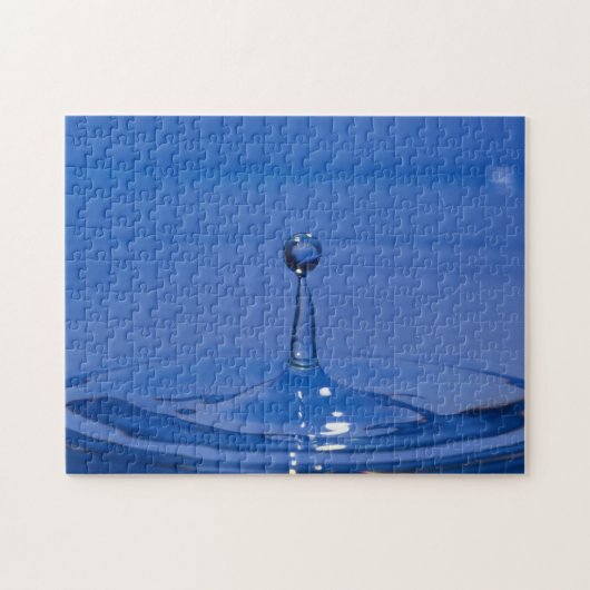 Blauwe druppel water in beweging op een puzzel legpuzzel (Horizontaal)