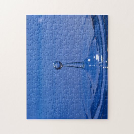 Blauwe druppel water in beweging op een puzzel legpuzzel (Verticaal)