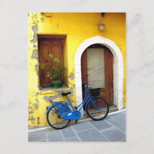 Blauwe fiets tegen gele muur briefkaart