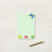 Blauwe rode en gele vlinders op lichtgroen post-it® notes (Op bureau)