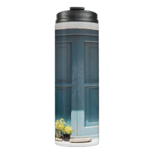 BLAUWE WOODEN DEUR OP WITTE CONCRETE WAL THERMOSBEKER