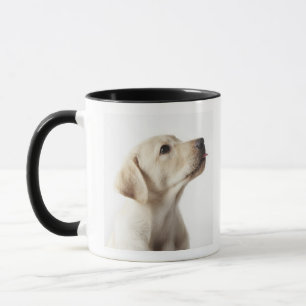 Blond labrador puppy die tong uitsteekt mok