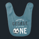 Boys Cute Blue Soccer 1st Birthday Baby Bib Baby Slabbetje<br><div class="desc">Deze schattige babybib van de eerste verjaardag heeft een blauw sportontwerp, met een voetbal en "superstar ___ draait er een", zodat u de naam van uw kind kunt toevoegen. Op de achterkant van de bib is een patroon voorzien van een football, voetbal, tennisracket en bal, trofee, basketbal en sterren. Het...</div>