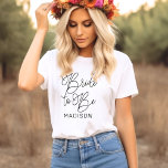 Bride om de zwarte Moderne Aangepaste Band van het T-shirt<br><div class="desc">Modern en casual chic zwart kalligrafie script "Bride to Be" vrouwen bruids bruids bruids T-shirt beschikt over aangepaste tekst die kan worden gepersonaliseerd met de voornaam van de bruid. Perfect voor de bruid om te draag op het vrijgezellenfeest en het huwelijksweekend!</div>
