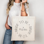 Bruid to Be Heart Black Kalligrafie Script Wedding Tote Bag<br><div class="desc">Deze canvas tas heeft een stijlvol cirkelvormig ontwerp met de uitdrukking "Bride to Be" elegant herhaald rond het centrum. Het midden toont een aanpasbare naam in delicaat schrift, geaccentueerd met een klein hart, waardoor een persoonlijke touch wordt toegevoegd aan dit prachtige ontwerp. Ideaal voor vrijgezellenfeesten, vrijgezellenfeesten of huwelijksvoorbereidingen. Personaliseer het...</div>