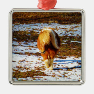 Bruin en roomminiatuur paard in de sneeuw. metalen ornament