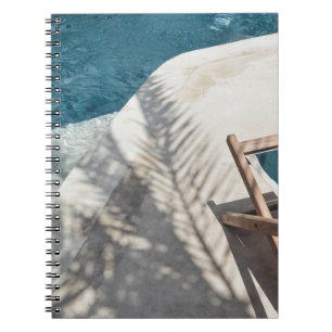 Bruine houten lounger nabij waterlichaam notitieboek
