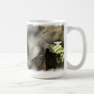 Bruine vlinder op wit koffiemok