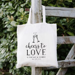 Cheers to Love Wedding Favor Tote Bag<br><div class="desc">Festive en chic bruiloft-welkome canvas tassen zijn voorzien van "kousen tot liefde" in zwarte  stijl-blokjes en scripttypografie met twee champagnefluiten die door een bruisend hart worden gecombineerd. Pas je naam aan met je trouwdatum eronder.</div>