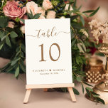 Chic Gold Script Cream bruiloft receptie Kaart<br><div class="desc">Chic light cream bruiloft receptie tafel nummer teken met "tafel" in een elegante gouden kalligrafie script met moerassen, het tafelnummer in klassieke gouden serif typografie, uw voornamen vergezeld door een hart en uw ontvangst datum. Creëer elk tabelnummer en voeg het één voor één toe aan uw winkelwagentje, en kijk dan...</div>