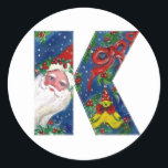 CHRISTMAS K BRIEF / SANTA CLAUS MET RODE RIBBON RONDE STICKER<br><div class="desc">K initiaal Letter-kerstmonogram. Kleurrijk,  wit en artistiek acrylschilderij voor Kerstmis. Santa Claus,  sneeuwwinternacht met bloemige ornamenten,  kat,  rode boog,  groene decoratieve planten,  rode linten,  holbessen,  poppen en speelgoed in de sneeuw door Bulgan Lumini (c) com</div>