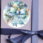 Christmas Pine Branch met Blue Bow en Ornamenten Ronde Sticker<br><div class="desc">Voeg een feestelijk tintje toe aan uw vakantiekaarten en geschenken met dit charmante waterverf Kerst sticker. Met een weelderige dennentak,  een grote blauwe boog en sprankelende ornamenten is het een winterwonderland! De "Merry Christmas" -tekst is volledig aanpasbaar,  zodat u deze kunt personaliseren met uw familienaam of bericht.</div>