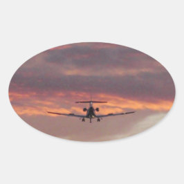 Commerciële straaljager landend bij zonsondergang ovale sticker