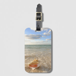 Conch Shell in zand op tropisch strand Bagagelabel