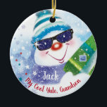 Cool Yule, Grandson, Snowman in Shades, Kerstmis Keramisch Ornament<br><div class="desc">Een leuke sneeuwman met een wollen pet en donkere schoppen houdt een kerstcadeautje op de voorkant van deze kerstversiering (COOL YULE) voor kleinzoon. Hij is omringd door kleine sterren en vallende sneeuwvlokken, en cadeaus met een snoepriet op een bed van witte sneeuw tegen een blauwe achtergrond is het schattige afbeelding...</div>
