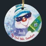 Cool Yule, Grandson, Snowman in Shades, Kerstmis Keramisch Ornament<br><div class="desc">Een leuke sneeuwman met een wollen pet en donkere schoppen houdt een kerstcadeautje op de voorkant van deze kerstversiering (COOL YULE) voor kleinzoon. Hij is omringd door kleine sterren en vallende sneeuwvlokken, en cadeaus met een snoepriet op een bed van witte sneeuw tegen een blauwe achtergrond is het schattige afbeelding...</div>