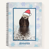 Cute Otter die met Kerstmis een kerstman heeft. Notitieboek (Voorkant)
