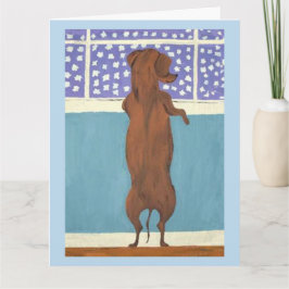 Dachshund bij het raam die naar de sneeuw kijkt kaart