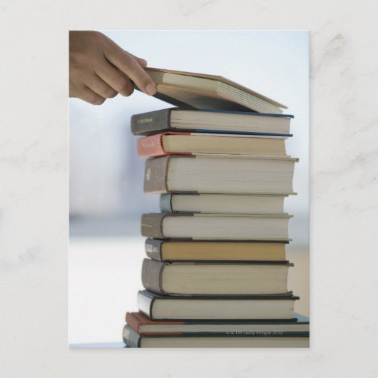 De hand die van het man een boek van een stapel briefkaart (Voorkant)