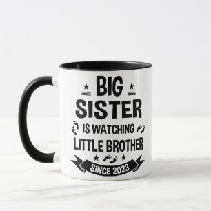 De kleine zusje zorgt voor de grote broer in mok