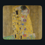 De minnaars die elkaar omhelzen van Gustav Klimt Snijplank<br><div class="desc">Zonlicht schittert van de wervelende gouden omhelzing die de geliefden omringt in het meesterwerk De Kus van Gustav Klimt. De scène is een paradox van intimiteit en isolement. Het paar staat op een afgrond, een veld van kleurrijke bloemen aan hun voeten, maar ze zijn zich niet bewust van de wereld...</div>