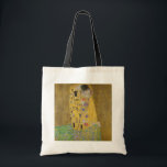 De minnaars omhelzen elkaar by Gustav Klimt Tote Bag<br><div class="desc">Zonlicht schittert van de wervelende gouden omhelzing die de geliefden omringt in het meesterwerk De Kus van Gustav Klimt. De scène is een paradox van intimiteit en isolement. Het paar staat op een afgrond, een veld van kleurrijke bloemen aan hun voeten, maar ze zijn zich niet bewust van de wereld...</div>