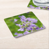 Delicate blauwe bloemen op een groen veld in een l kartonnen onderzetters (Schuin)