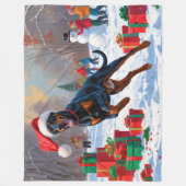 Dobermann loopt in de sneeuw met kerstmuts fleece deken (Voorkant)