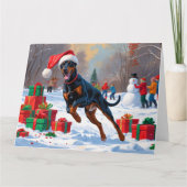 Dobermann loopt in de sneeuw met kerstmuts kaart (Voorkant)