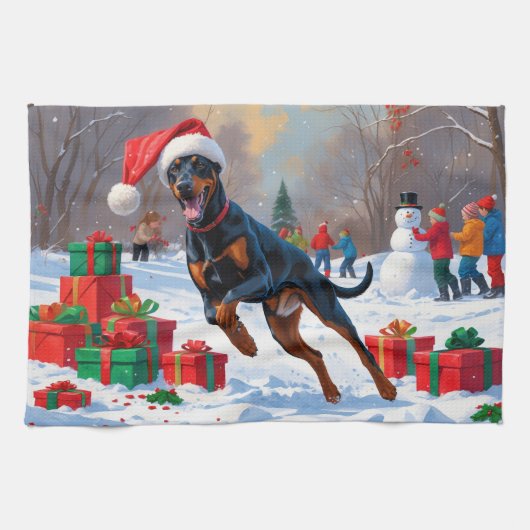 Dobermann loopt in de sneeuw met kerstmuts theedoek (Horizontaal)