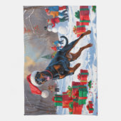 Dobermann loopt in de sneeuw met kerstmuts theedoek (Verticaal)