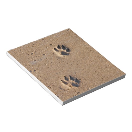 Dog paw drukt op een zandig strand notitieblok (Schuin)