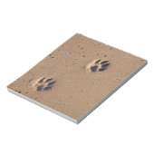 Dog paw drukt op een zandig strand notitieblok (Linkerzijde)