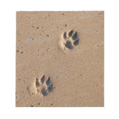 Dog paw drukt op een zandig strand notitieblok (Voorkant)