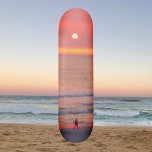 Door Golden Oranje zonneklare skateboard<br><div class="desc">Dit skateboard bevat een afbeelding van een persoon die door de gouden roze en oranje stralen van de zonsondergang loopt. De kleurrijke stralen creëer een baan die de wandelaar silhoueteert.</div>