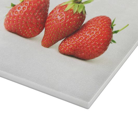 Drie aardbeien op witte cbcnm snijplank (Hoek)